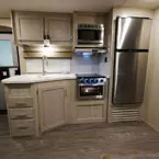 Kitchen Galley- Two Cabinet Doors and Microwave Overhead of Sink with Sink Covers, Oven/Stove Top, Three Drawers and One Cabinet Door Below. Next to Stainless Steel Refrigerator.
 May Show Optional Features. Features and Options Subject to Change Without Notice.