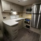 Kitchen Galley Area with Cabinets and Microwave Overhead of Kitchen Sink and Oven/Stove Top. Stainless Steel Refrigerator Next to Pantry. Three Drawers and Two Doors Below.
 May Show Optional Features. Features and Options Subject to Change Without Notice.