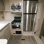 Stainless Steel Microwave Mounted Overhead of Three Burner Cook Top/Stove, Next to Stainless Steel Refrigerator and Two Door Pantry.
 May Show Optional Features. Features and Options Subject to Change Without Notice.