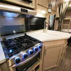 Three Burner Cook Top with Glass Shown Open. Sink with Sink Covers and Stainless Steel Faucet.
 May Show Optional Features. Features and Options Subject to Change Without Notice.