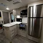 Kitchen Galley Area with Microwave and Cabinets Mounted Overhead of Stove/Oven, Stainless Steel Refrigerator, Three Drawers and One Cabinet Door Below. 
 May Show Optional Features. Features and Options Subject to Change Without Notice.