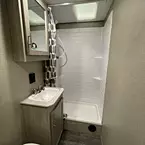 Bathroom with marine toilet with foot flush, sink with storage cabinet, mirrored medicine cabinet, and shower
 May Show Optional Features. Features and Options Subject to Change Without Notice.