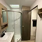Bathroom with sink and mirrored medicine cabinet, shower with sliding glass door, and skylight and door to bedroom shown open May Show Optional Features. Features and Options Subject to Change Without Notice.