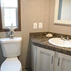 Bathroom with toilet and sink with storage cabinets and mirrored medicine cabinet May Show Optional Features. Features and Options Subject to Change Without Notice.